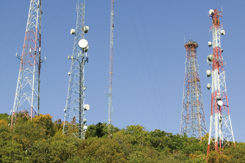 5 cell phone towers on a hill covered in trees