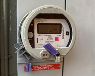 Gray smart meter attached to electric box on house