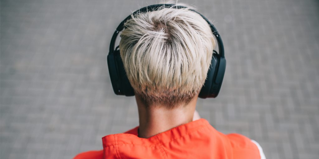 Back of head of a young person with blond hair wearing large black wireless headphones