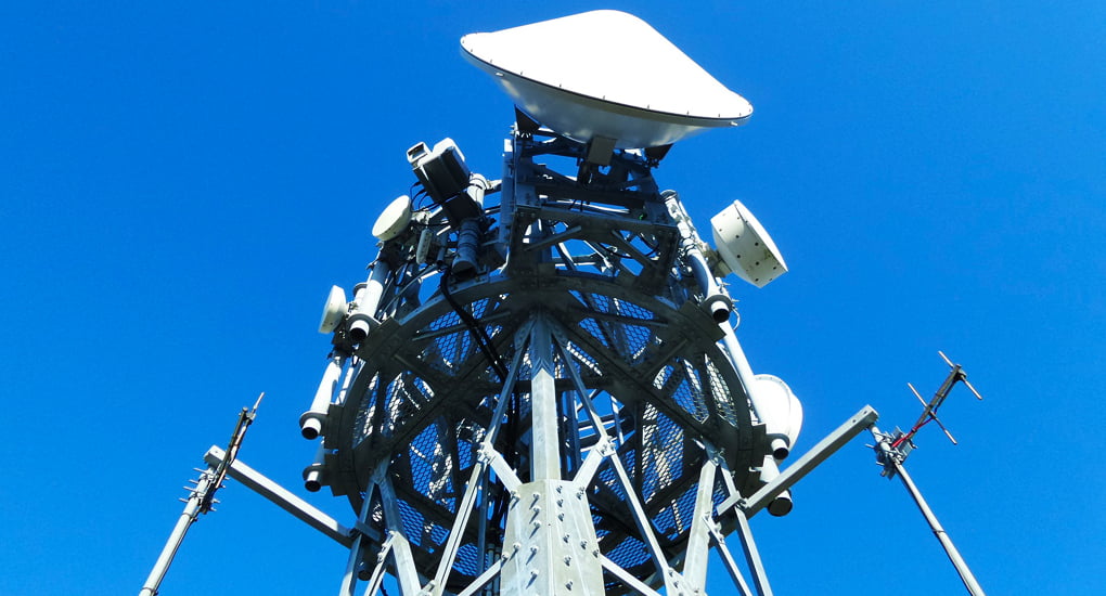 The top of a gray wifi tower with blue sky in the background