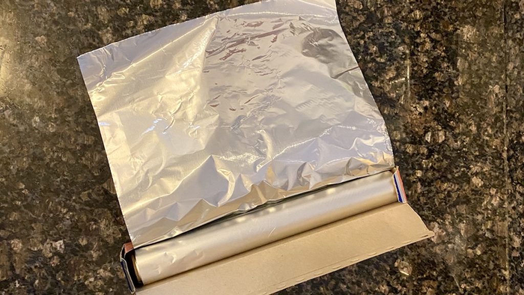unrolled aluminum foil on a black counter top
