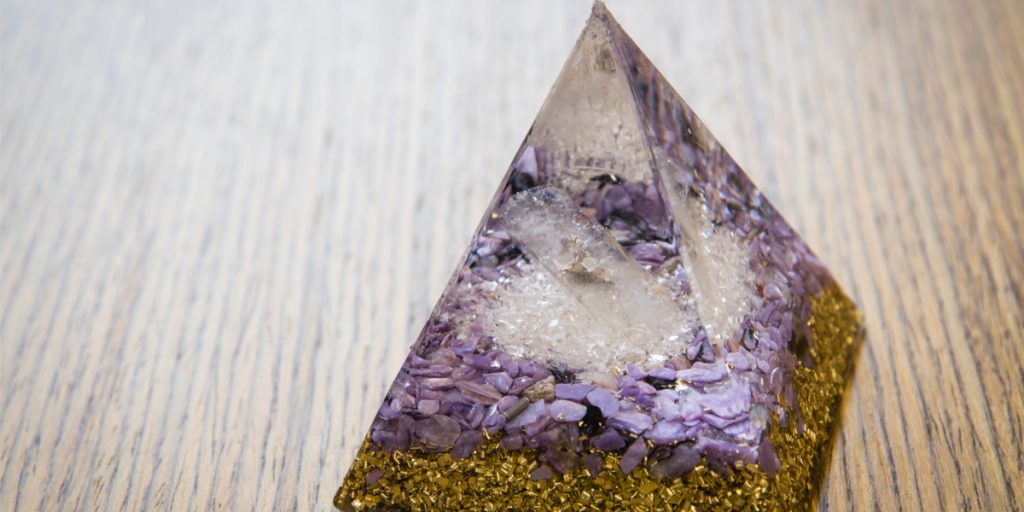 Orgonite pyramid crystal with golden metal shavings at the base