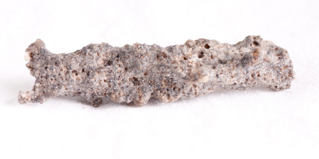 Tan colored Fulgurite mineral rectangular in shape against white background
